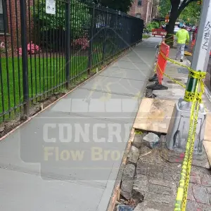 Leveled sidewalk section along an iron fence after repair